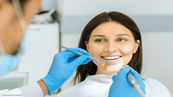 Auf dem Bild ist eine junge Frau zu sehen, welche gerade beim Zahnarzt behandelt wird.